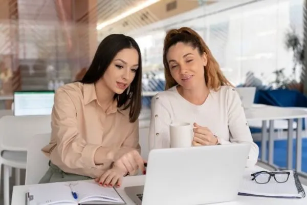 Dos mujeres trabajando con una laptop en una oficina
