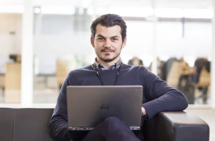 hombre con computadora en oficina mirando a camara