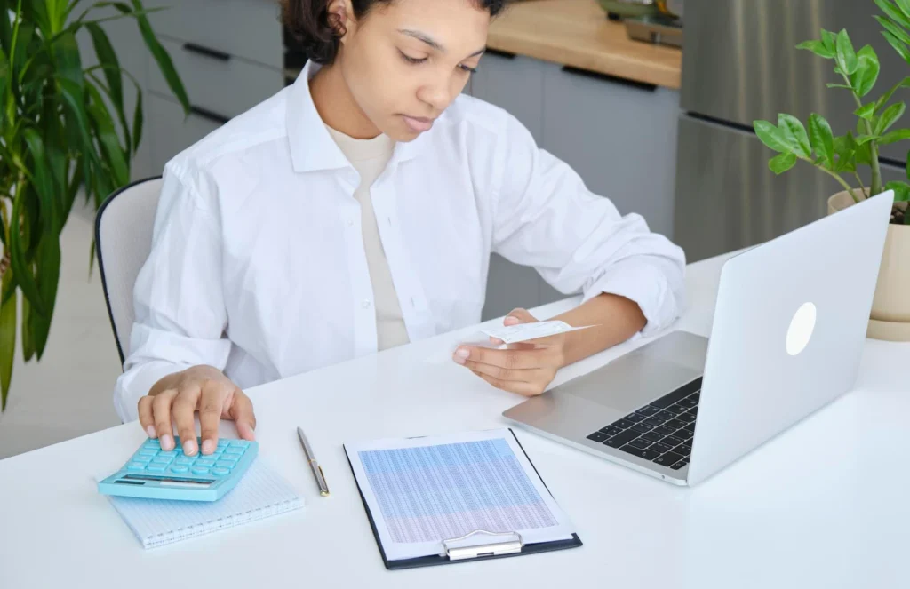 Analista de nómina revisa un comprobante de sueldo con una calculadora, una planilla impresa y una notebook sobre el escritorio