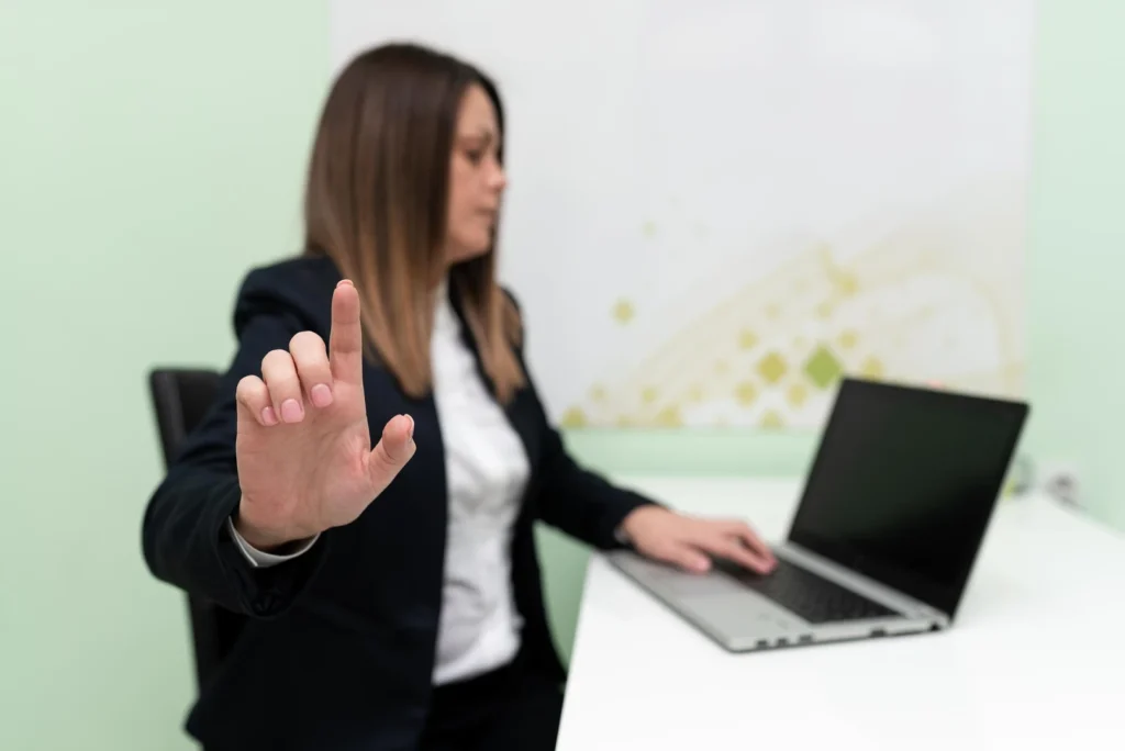 Ejecutiva frente a su notebook levanta la mano en gesto de alto