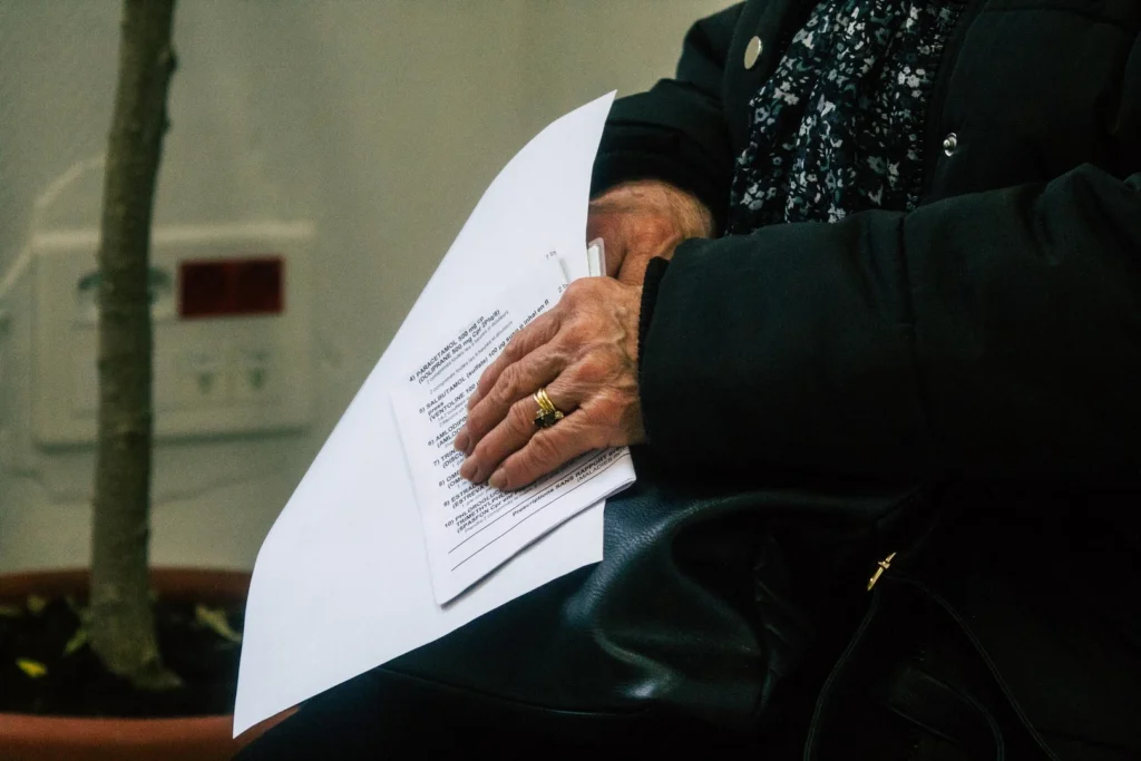 Persona mayor sostiene un documento impreso sobre su regazo