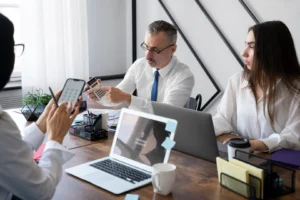 Equipo de RR. HH. reunido en una oficina revisa documentación laboral con una calculadora, un celular y una notebook sobre la mesa