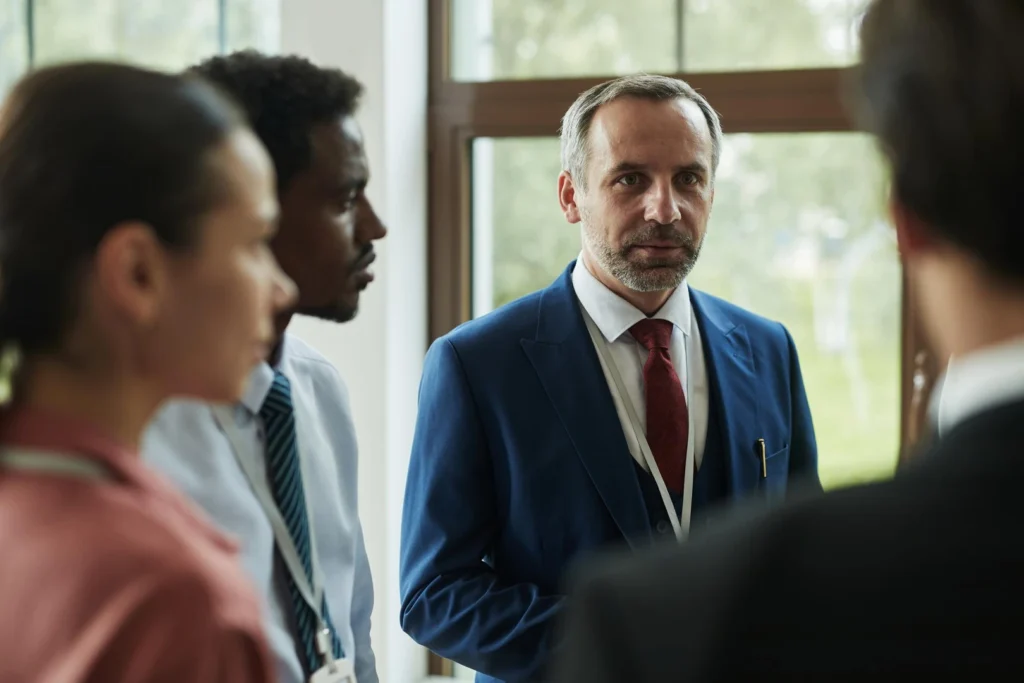Un hombre de mediana edad conduce una reunión de trabajo con un grupo diverso de colegas